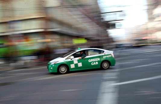 A Toyota Prius hybrid taxi drives across Market Street on in San Francisco